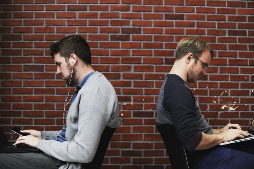 Two workers sitting back-to-back not showing cross team collaboration