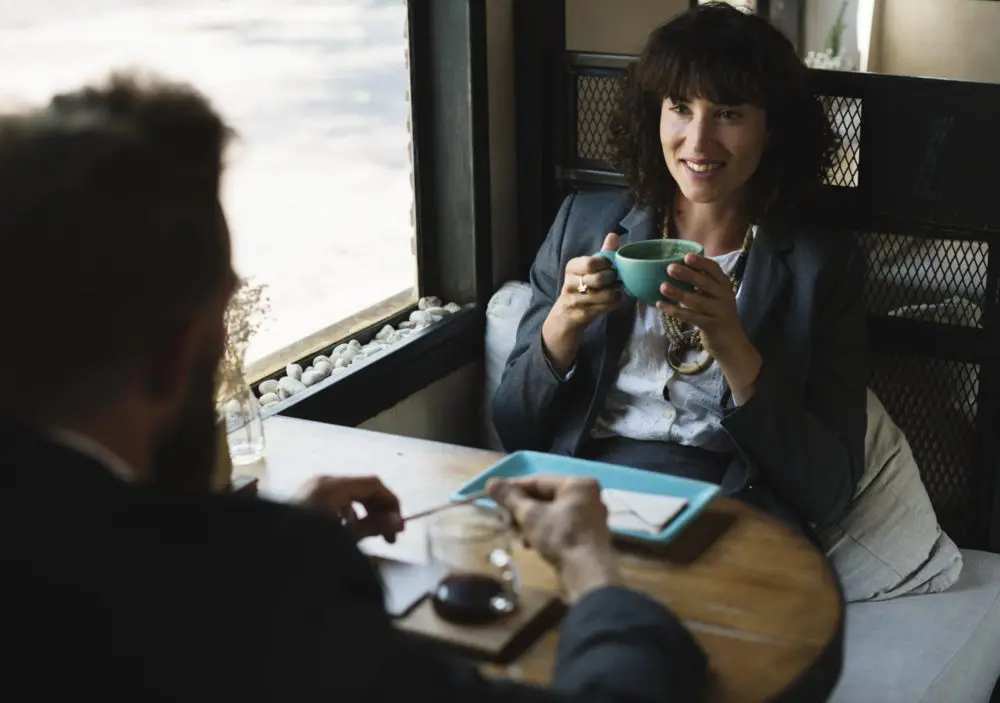 Two people in a cafe discussing CRM