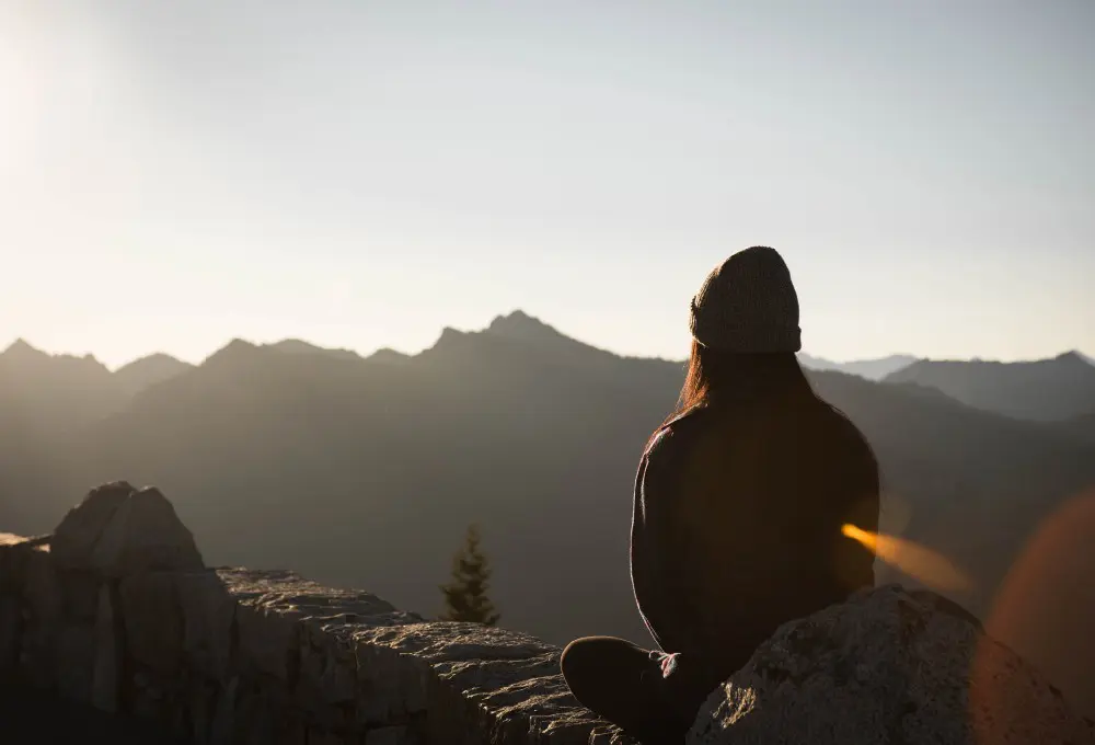 woman meditating with focus looking out onto mountains