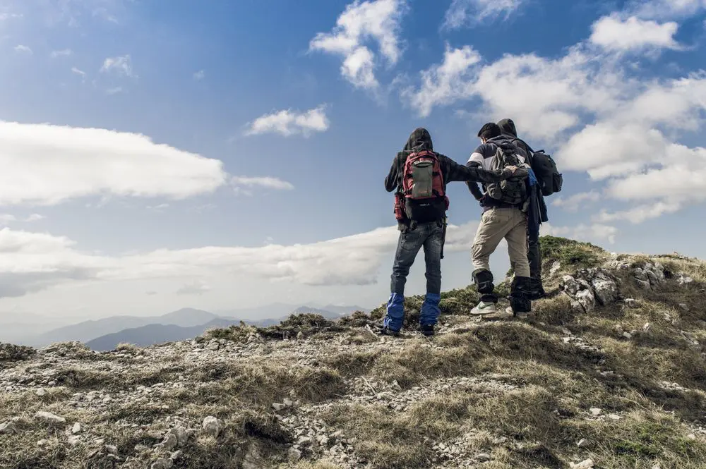 three persons on hilltop during daytime