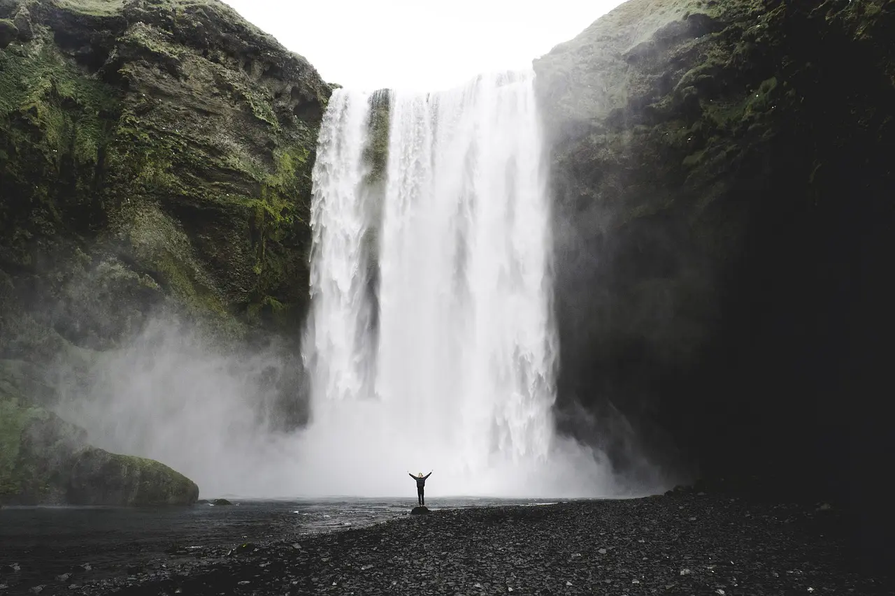 Mann steht vor Wasserfall