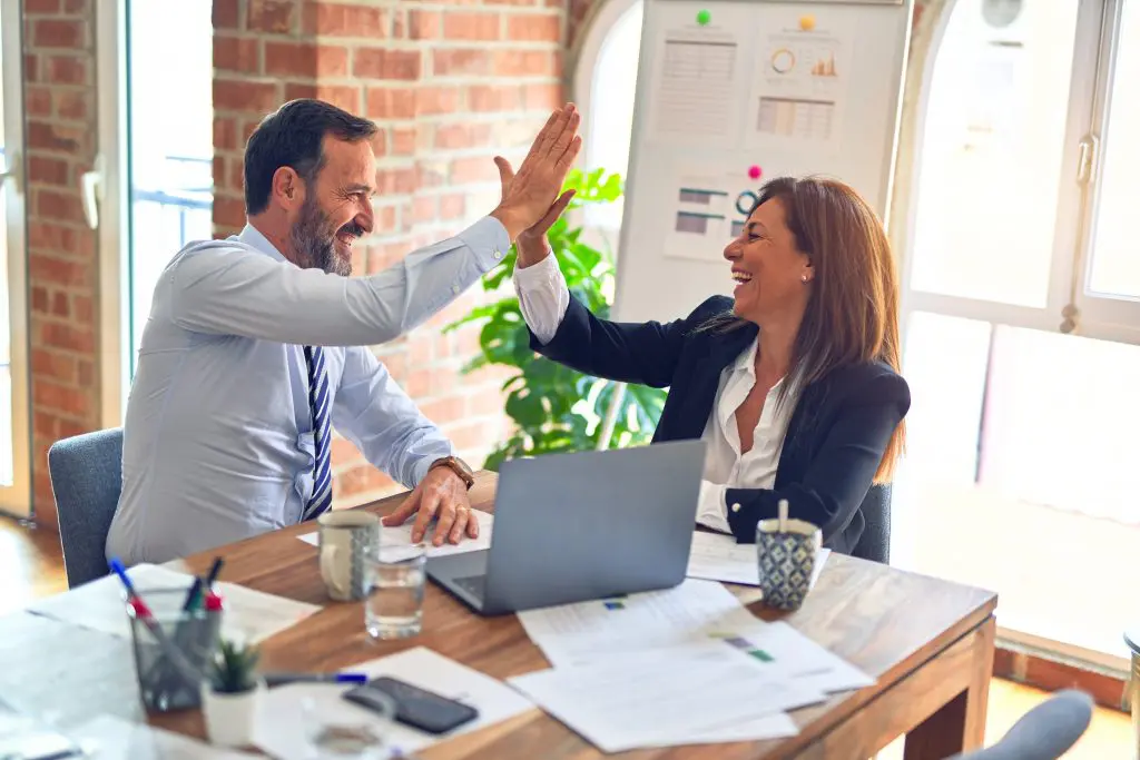 team members at work desk high five one another