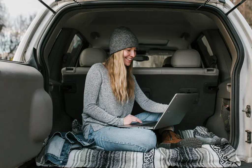 young woman working on laptop in the back of a car