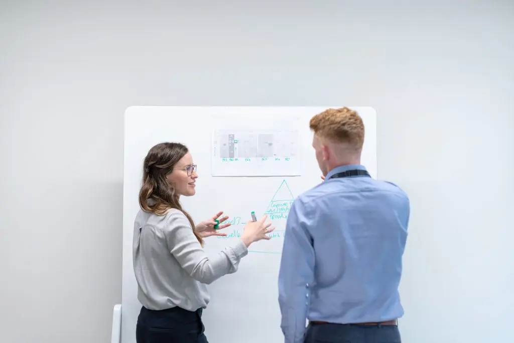 man and woman discussing planning in front of whiteboard